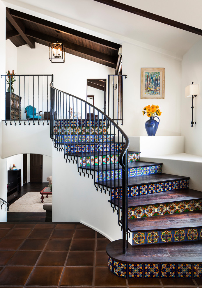 This is an example of a mid-sized traditional wood curved staircase in Santa Barbara with tile risers and metal railing.