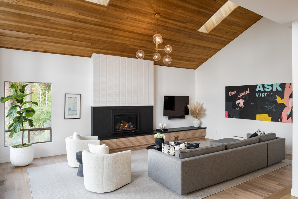 Photo of a midcentury living room in Portland with white walls, light hardwood floors, a standard fireplace, beige floor, vaulted and wood.