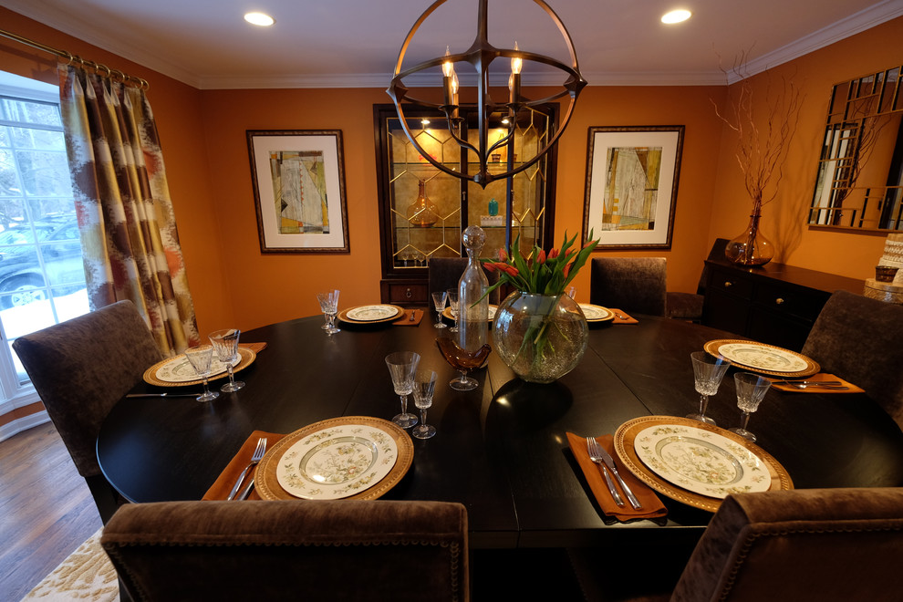 Example of a large transitional dark wood floor enclosed dining room design with orange walls and no fireplace