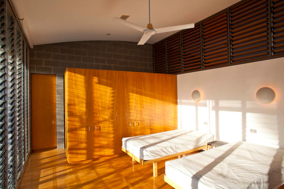 Contemporary bedroom in Sydney with white walls and medium hardwood floors.