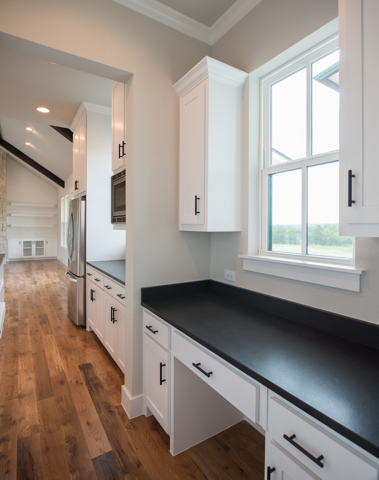 Inspiration for a mid-sized country u-shaped kitchen in Dallas with recessed-panel cabinets, white cabinets, wood benchtops, stainless steel appliances, black benchtop, medium hardwood floors and brown floor.