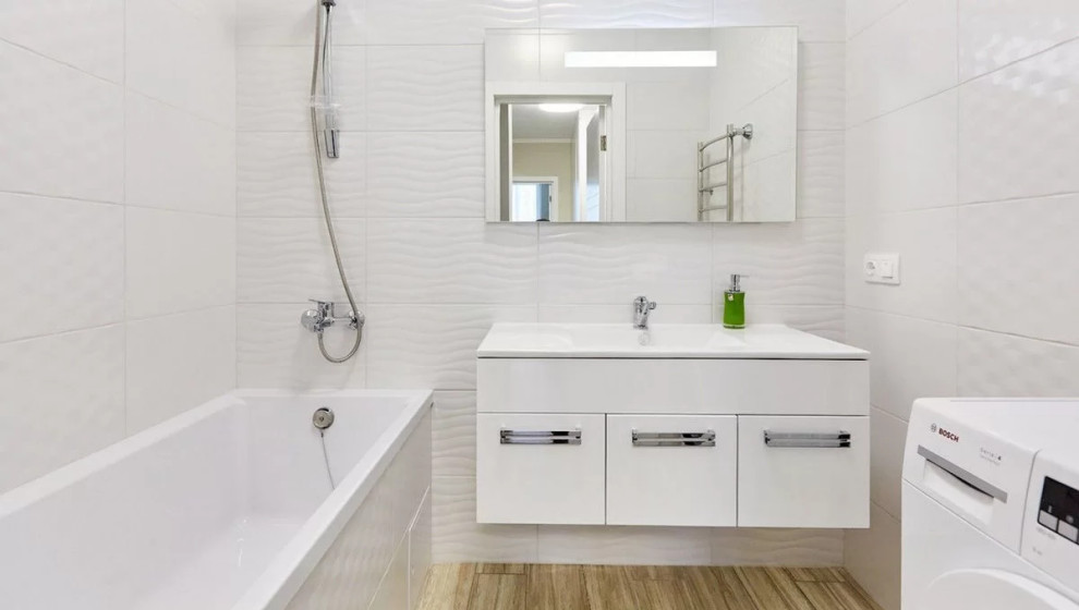 На фото: ванная комната среднего размера, в белых тонах с отделкой деревом в современном стиле с плоскими фасадами, белыми фасадами, полновстраиваемой ванной, душем над ванной, инсталляцией, белой плиткой, керамической плиткой, белыми стенами, полом из керамической плитки, накладной раковиной, столешницей из искусственного камня, бежевым полом, шторкой для ванной, белой столешницей, зеркалом с подсветкой, тумбой под одну раковину и подвесной тумбой с