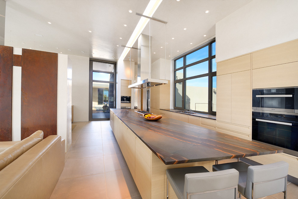 Inspiration for a large modern single-wall open plan kitchen in Phoenix with an undermount sink, flat-panel cabinets, light wood cabinets, concrete benchtops, stainless steel appliances, porcelain floors, with island and beige floor.