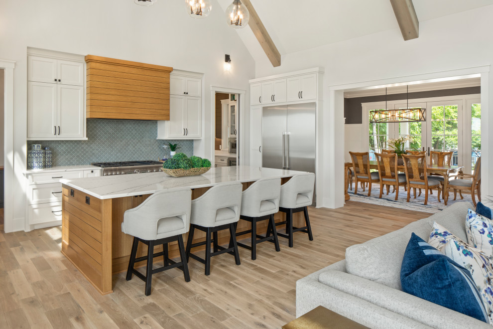 Photo of a large transitional u-shaped eat-in kitchen in Minneapolis with a farmhouse sink, shaker cabinets, white cabinets, quartzite benchtops, grey splashback, shiplap splashback, stainless steel appliances, medium hardwood floors, with island, beige floor, white benchtop and vaulted.