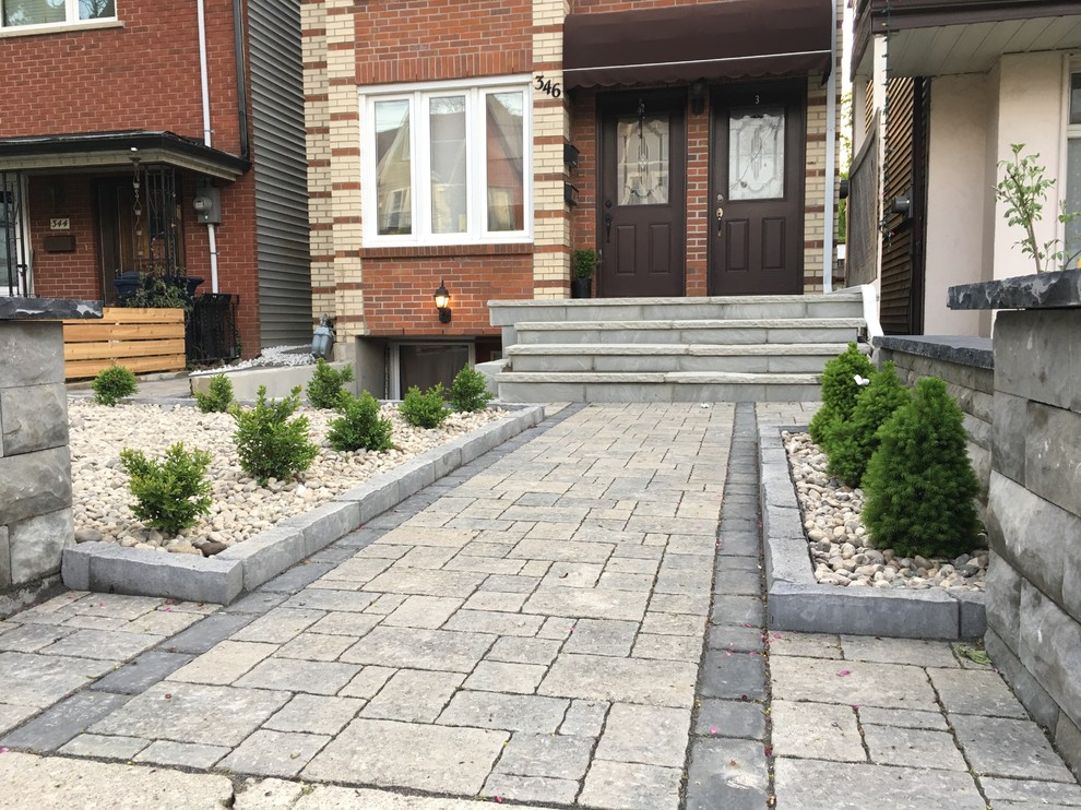 Photo of a mid-sized traditional front yard full sun formal garden for summer in Toronto with a retaining wall and brick pavers.