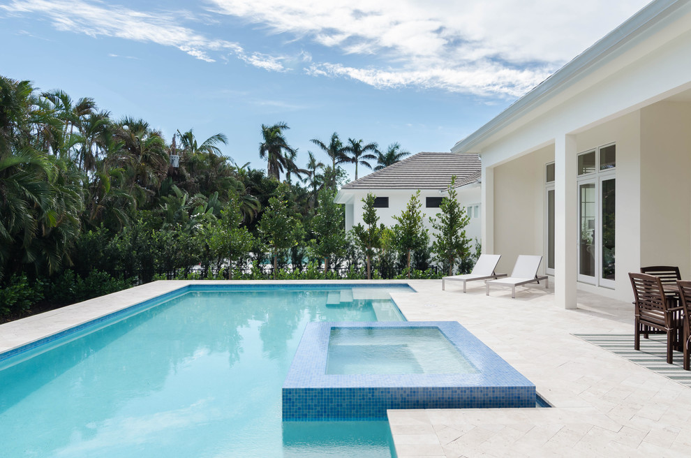 Large contemporary backyard rectangular lap pool in Miami with a hot tub and natural stone pavers.