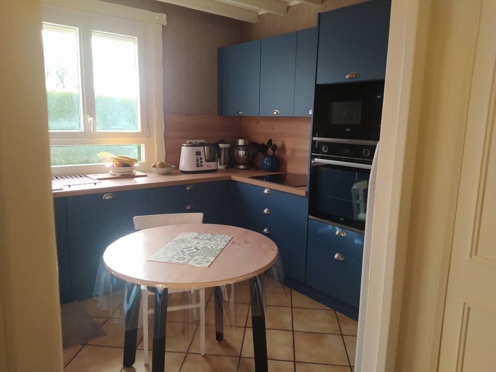 This is an example of a medium sized traditional u-shaped enclosed kitchen in Paris with a double-bowl sink, blue cabinets, laminate countertops, black appliances, no island, beaded cabinets, brown splashback, wood splashback, ceramic flooring, beige floors and brown worktops.