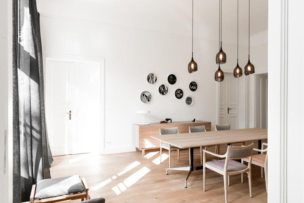 Photo of a large scandinavian separate dining room in Berlin with white walls and light hardwood floors.
