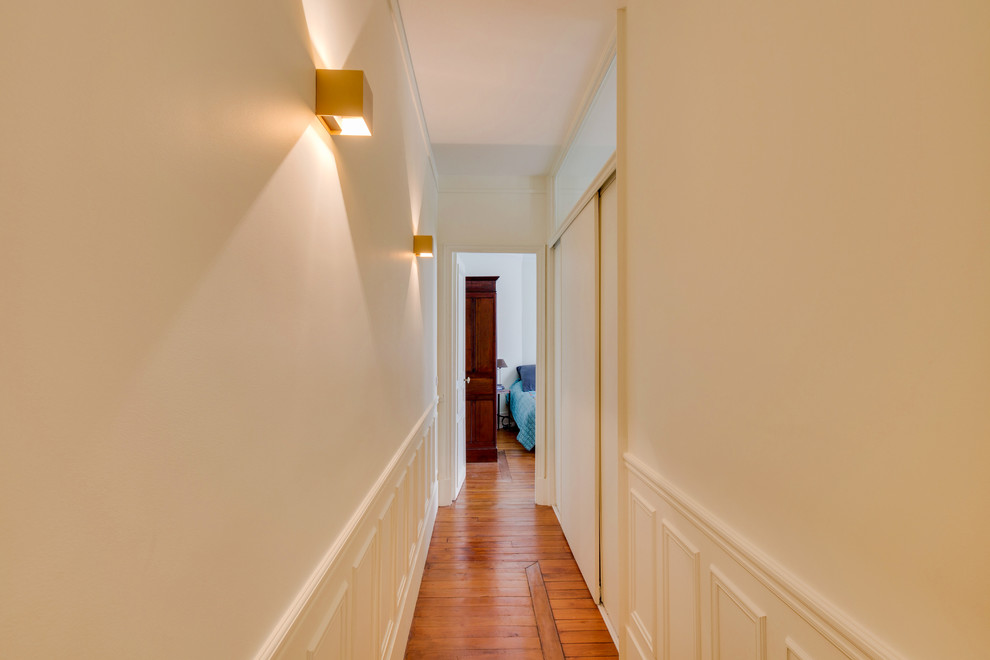 Photo of a mid-sized transitional hallway in Paris with white walls, dark hardwood floors and brown floor.