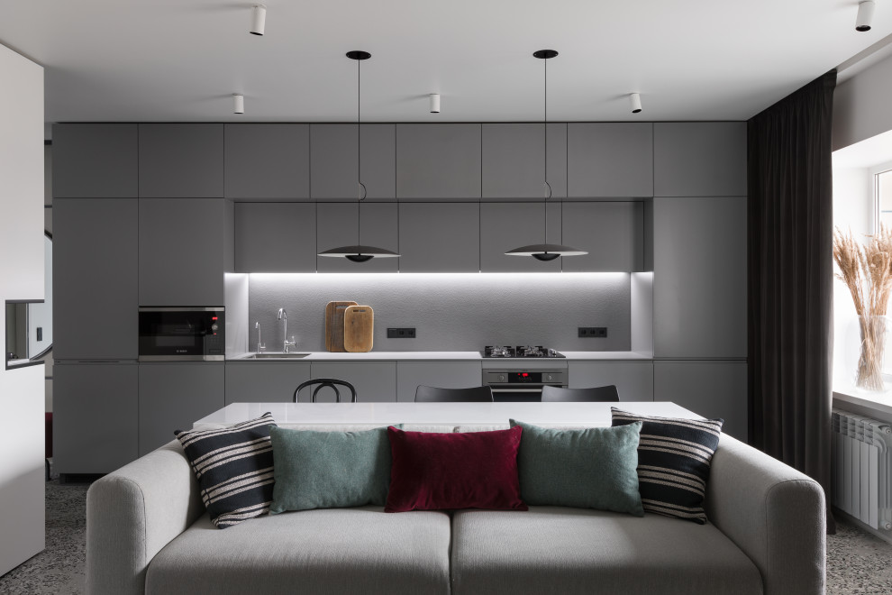 This is an example of a mid-sized contemporary single-wall open plan kitchen in Moscow with an undermount sink, flat-panel cabinets, grey cabinets, grey splashback, black appliances, terrazzo floors, no island, grey floor and grey benchtop.