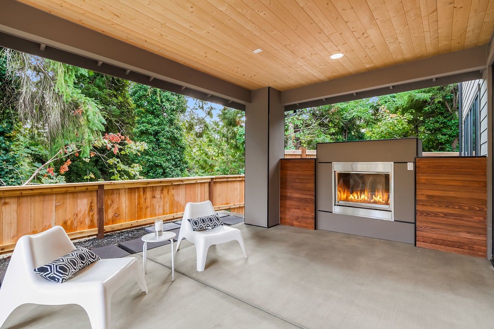 Design ideas for a mid-sized transitional backyard patio in Seattle with concrete slab, a roof extension and with fireplace.