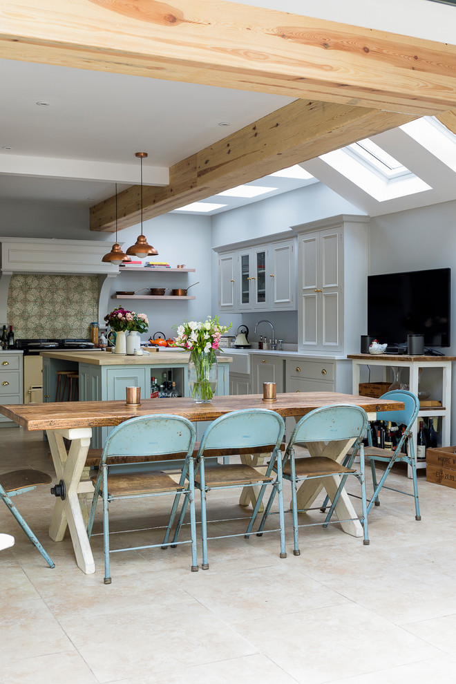 Inspiration for a mid-sized country kitchen/dining combo in London with grey walls, limestone floors and beige floor.
