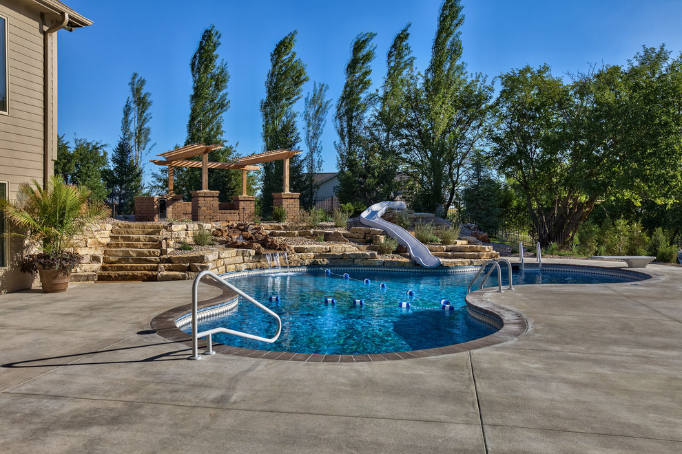 Design ideas for a large country backyard custom-shaped pool in Omaha with a water slide and concrete pavers.