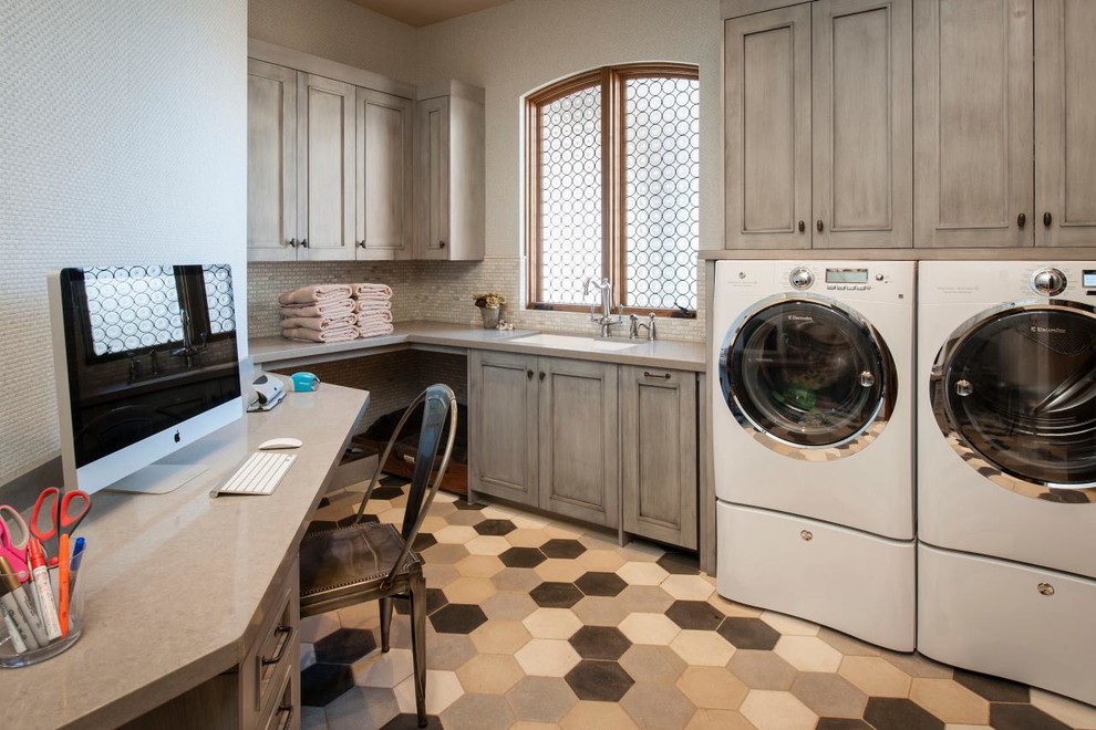 This is an example of a large transitional l-shaped utility room in New York with distressed cabinets, an undermount sink, quartz benchtops, white walls, porcelain floors, a side-by-side washer and dryer, multi-coloured floor and recessed-panel cabinets.