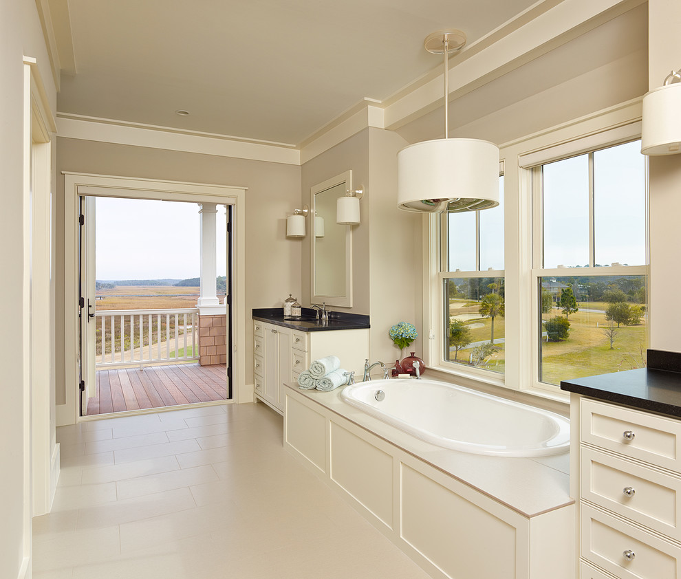 Photo of a beach style bathroom in Charleston with recessed-panel cabinets, white cabinets and a drop-in tub.