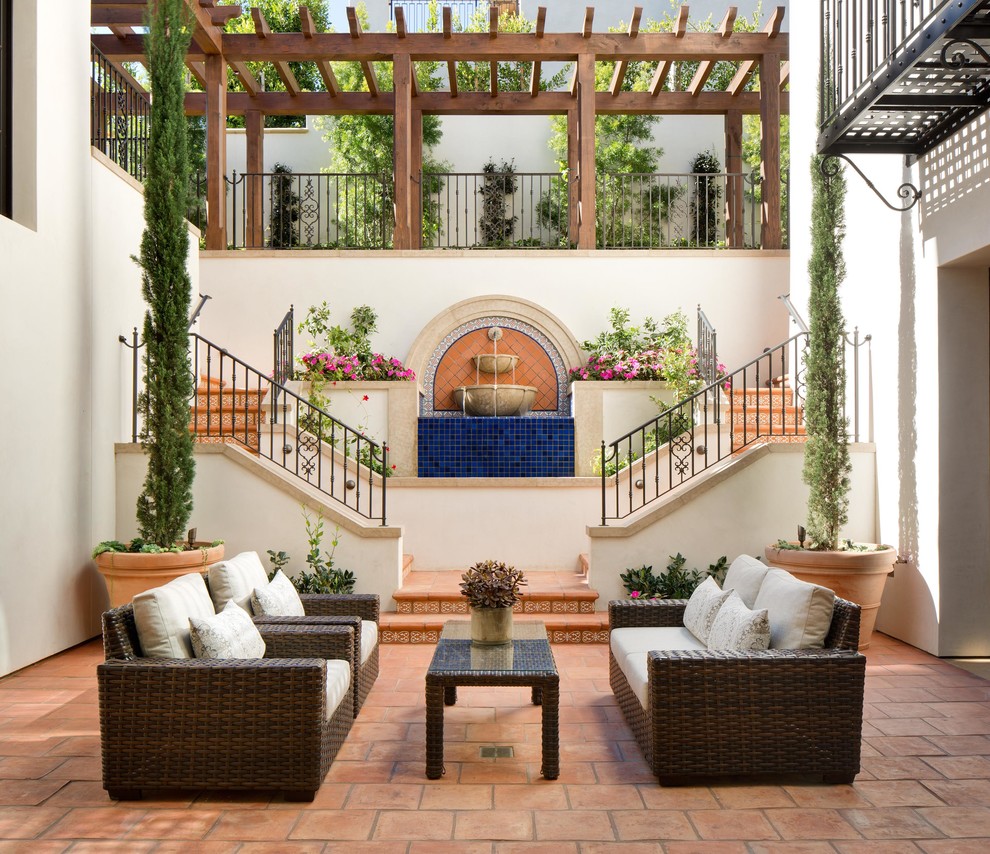 Inspiration for a mediterranean courtyard patio in Orange County with a water feature, tile and no cover.