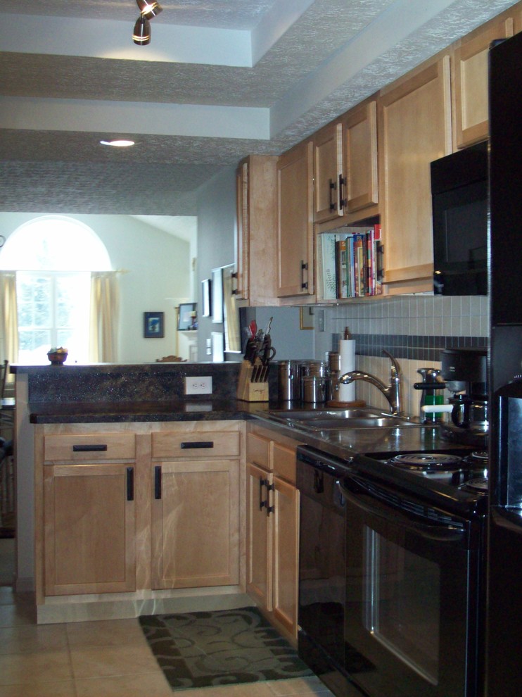 Kitchen - transitional ceramic tile kitchen idea in Columbus with recessed-panel cabinets, light wood cabinets, granite countertops, multicolored backsplash, ceramic backsplash and black appliances