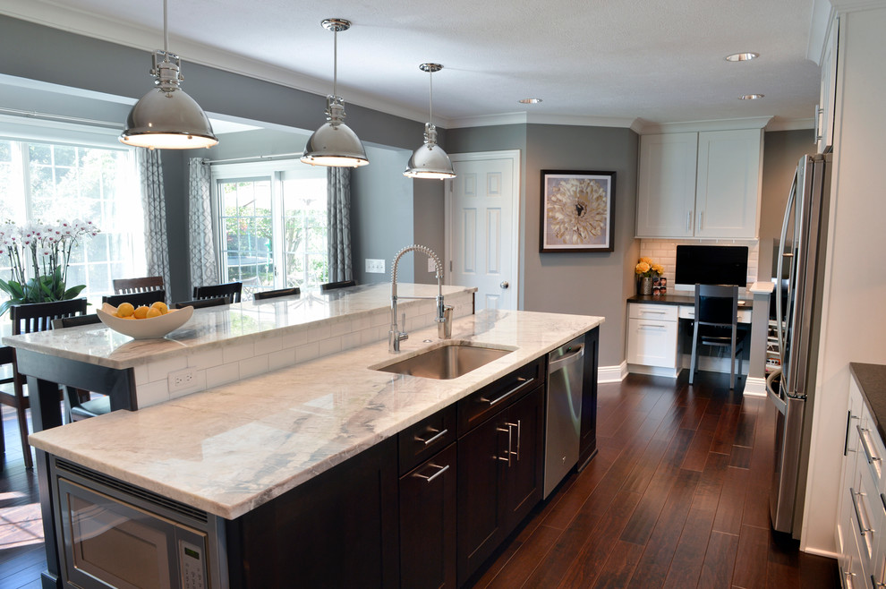 Example of a transitional dark wood floor kitchen design in Cleveland with a drop-in sink, recessed-panel cabinets, white backsplash, ceramic backsplash, stainless steel appliances and an island