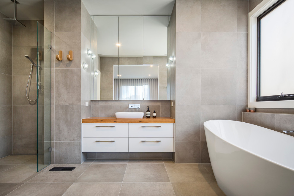 Inspiration for a contemporary bathroom in Melbourne with flat-panel cabinets, white cabinets, a freestanding tub, a curbless shower, gray tile, grey walls, a vessel sink, wood benchtops and brown benchtops.