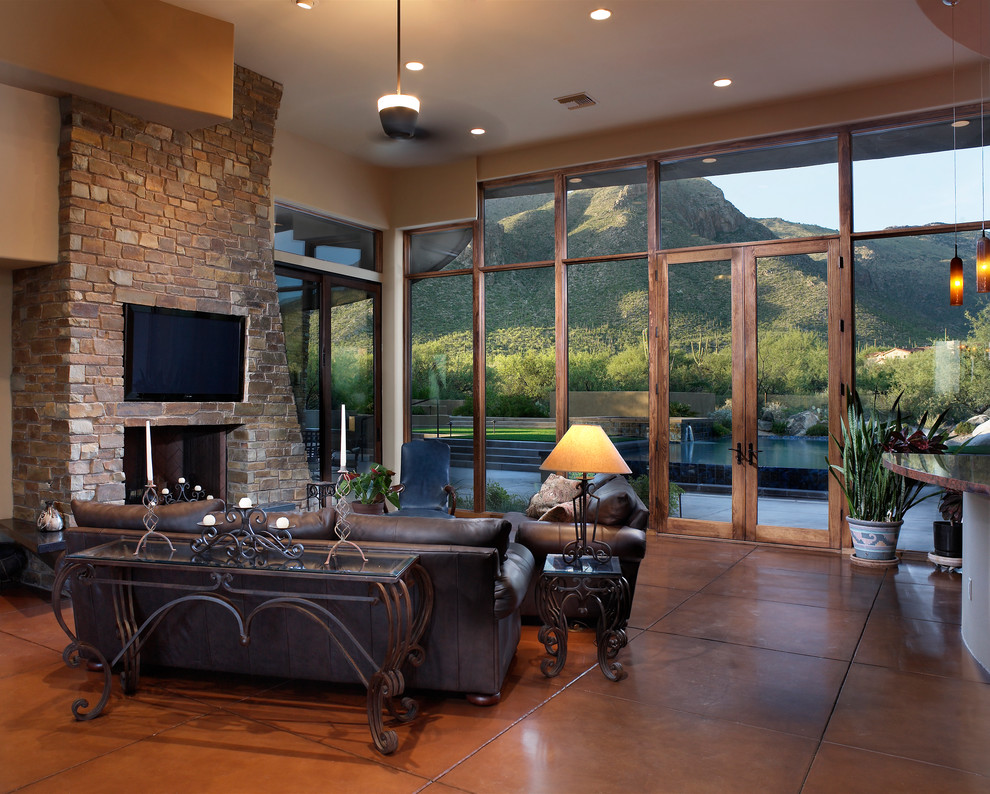 Traditional living room in Phoenix with concrete floors, a stone fireplace surround and orange floor.