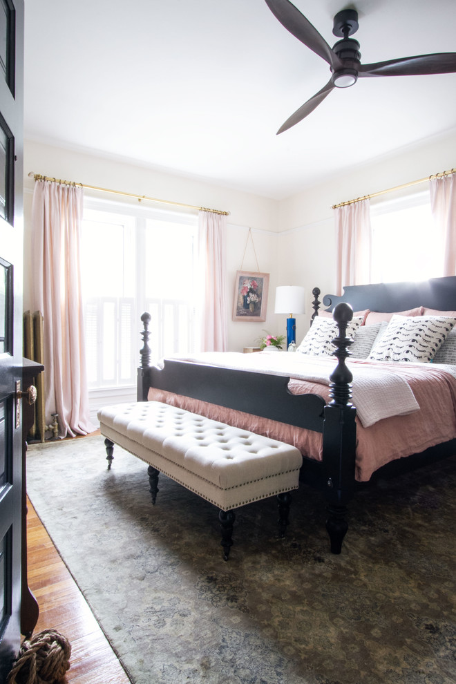 This is an example of a mid-sized eclectic master bedroom in Chicago with pink walls, medium hardwood floors and no fireplace.