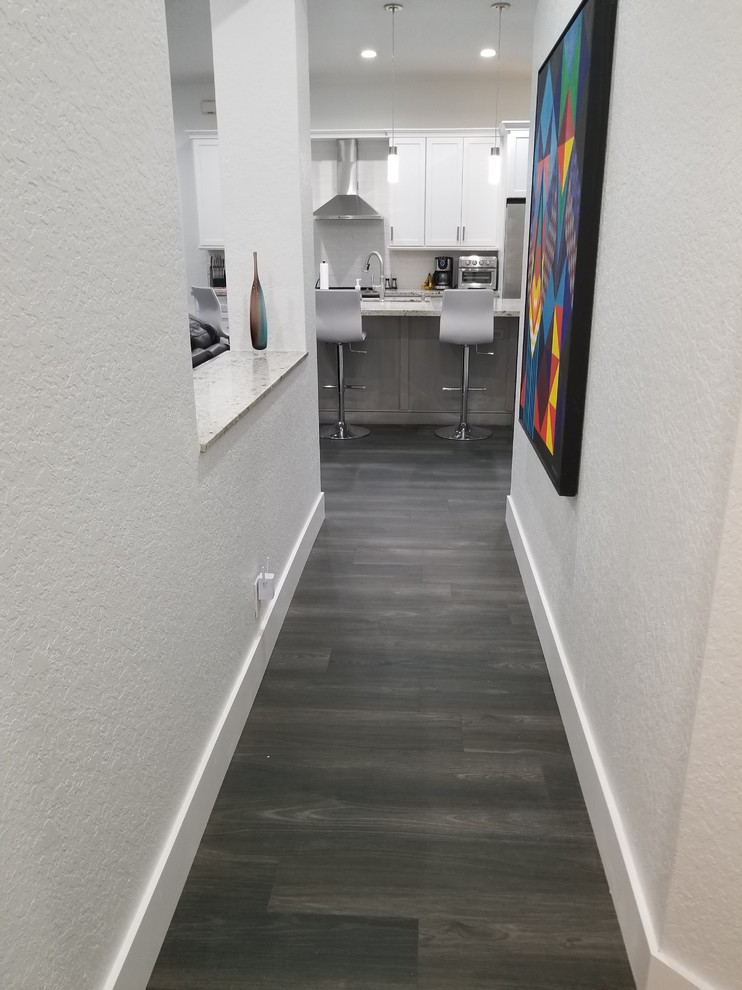 Design ideas for a mid-sized transitional single-wall eat-in kitchen in Miami with an undermount sink, shaker cabinets, white cabinets, granite benchtops, white splashback, subway tile splashback, stainless steel appliances, porcelain floors, with island, black floor and white benchtop.