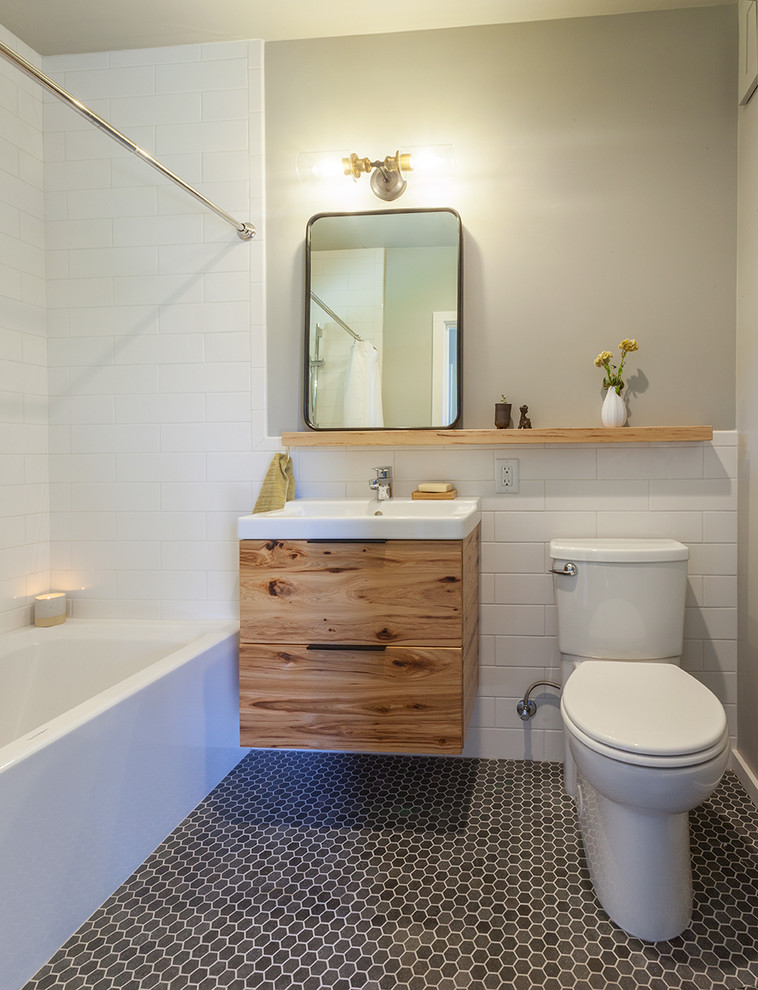 Inspiration for a transitional 3/4 subway tile gray floor alcove bathtub remodel with flat-panel cabinets, medium tone wood cabinets, a two-piece toilet, white walls and a console sink