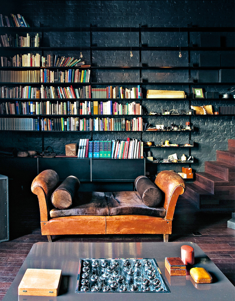 This is an example of a large contemporary living room in London with a library, black walls and dark hardwood floors.