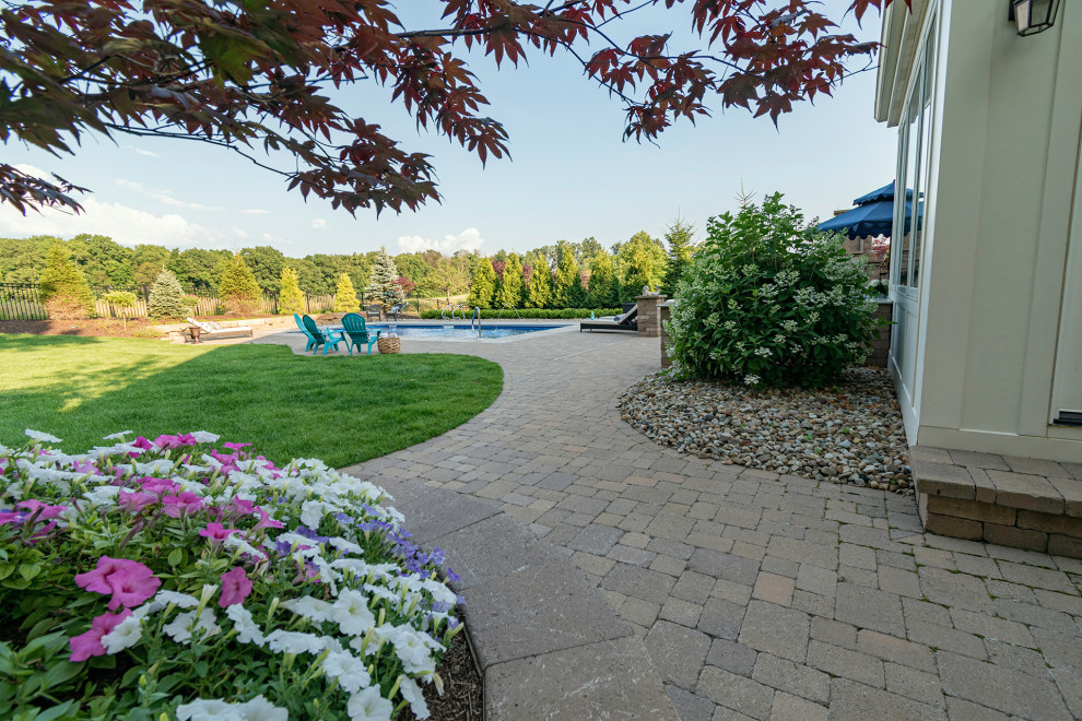 This is an example of an expansive contemporary backyard custom-shaped pool in Other with brick pavers.