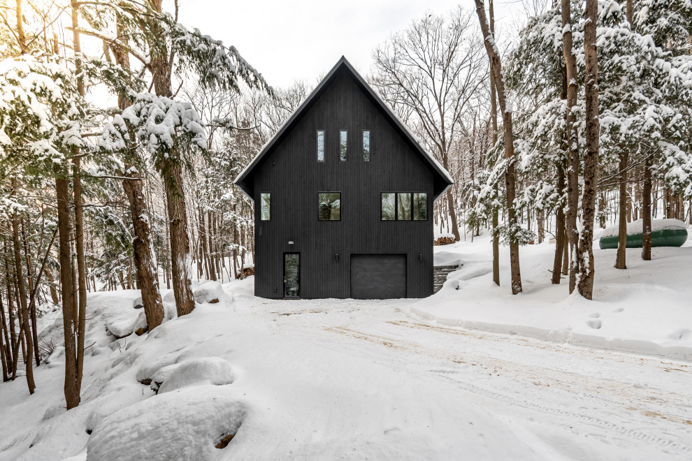 This is an example of a small scandinavian two-storey black house exterior in Toronto with wood siding, a gable roof, a metal roof and a black roof.