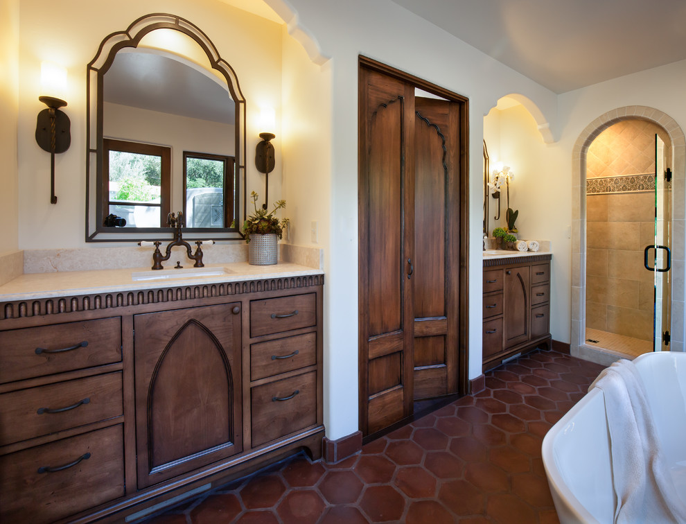 Design ideas for a large mediterranean master bathroom with an undermount sink, recessed-panel cabinets, dark wood cabinets, limestone benchtops, a freestanding tub, an alcove shower, a two-piece toilet, beige tile, terra-cotta tile, white walls and terra-cotta floors.