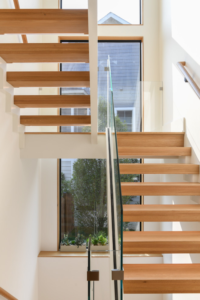 Imagen de escalera suspendida actual grande sin contrahuella con escalones de madera y barandilla de vidrio