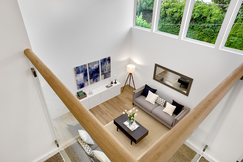 This is an example of a large modern formal open concept living room in Seattle with white walls and light hardwood floors.