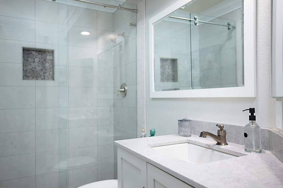 Photo of a small traditional kids bathroom in San Diego with shaker cabinets, white cabinets, an alcove shower, a two-piece toilet, gray tile, ceramic tile, grey walls, porcelain floors, an undermount sink, engineered quartz benchtops, brown floor, a sliding shower screen and grey benchtops.