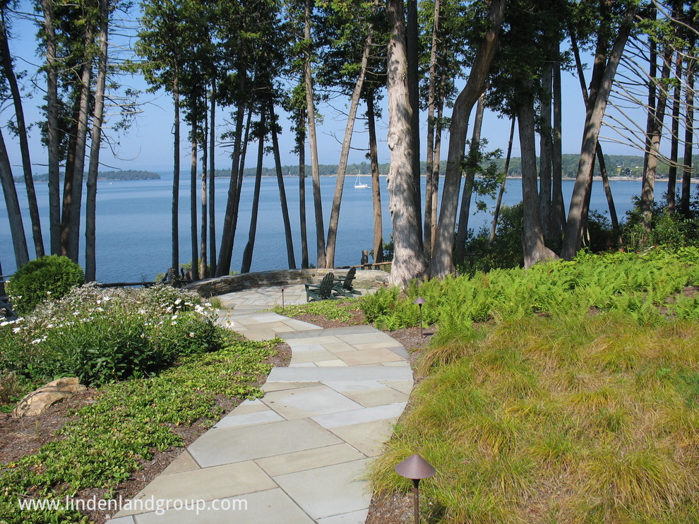 Expansive contemporary sloped full sun garden in Burlington with a retaining wall and natural stone pavers.