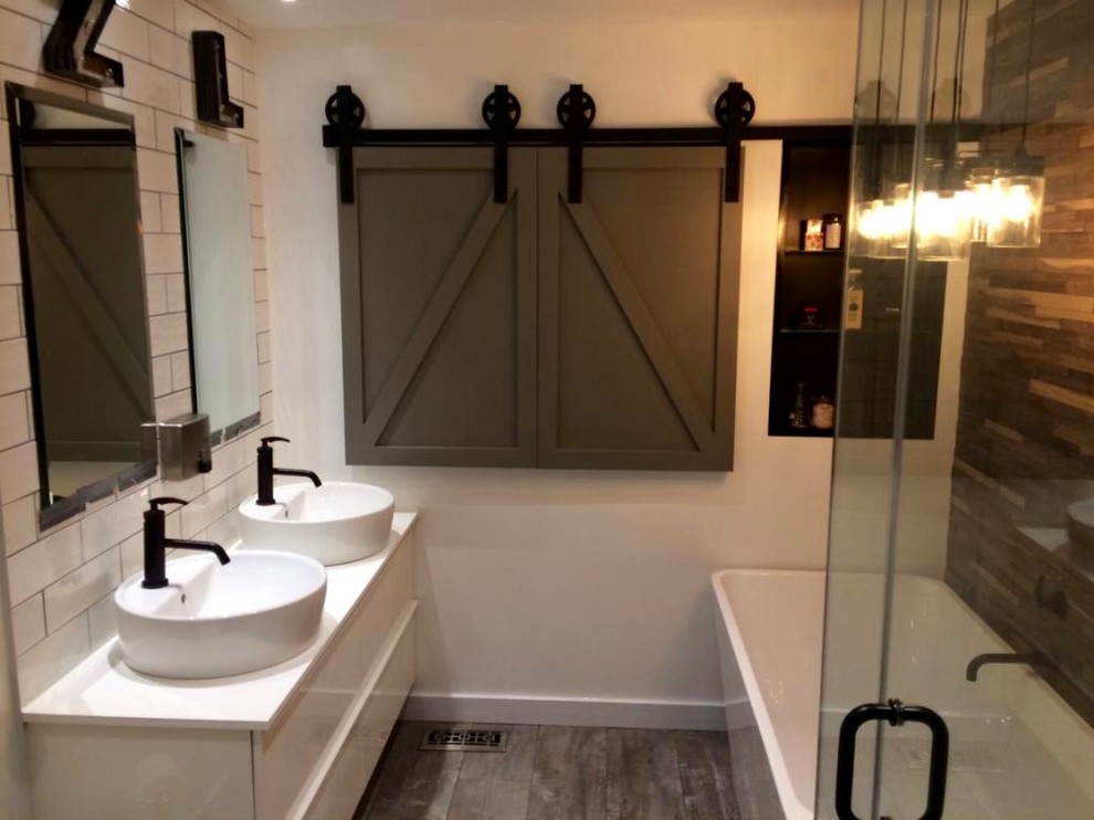 This is an example of a mid-sized country kids bathroom in Toronto with shaker cabinets, white cabinets, a freestanding tub, a one-piece toilet, white tile, mosaic tile, white walls, a vessel sink and engineered quartz benchtops.
