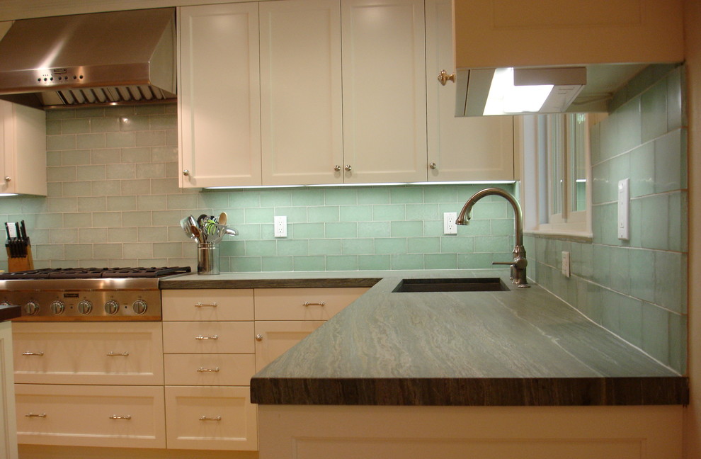 Photo of a mid-sized traditional l-shaped open plan kitchen in San Francisco with a drop-in sink, shaker cabinets, white cabinets, green splashback, light hardwood floors, with island, granite benchtops, glass tile splashback, stainless steel appliances, brown floor and green benchtop.