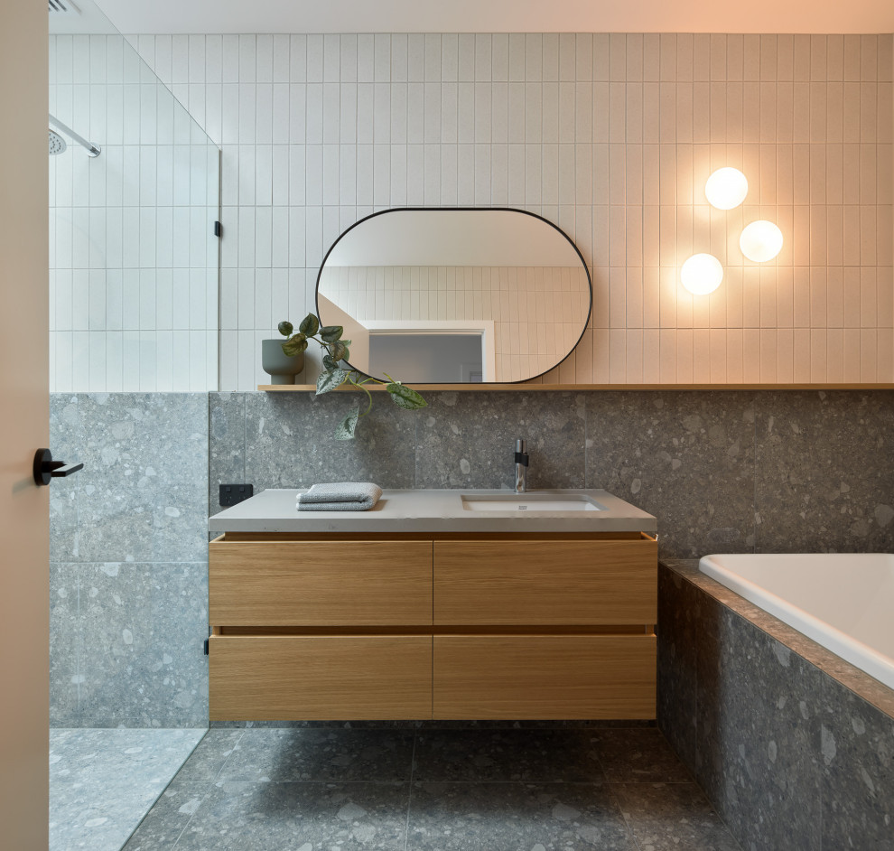Réalisation d'une grande salle de bain design en bois clair avec un placard à porte plane, une baignoire posée, un sol en marbre, un plan de toilette en surface solide, un sol gris, une cabine de douche à porte battante, un plan de toilette gris, meuble simple vasque et meuble-lavabo suspendu.