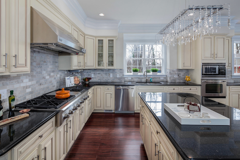 Inspiration for a traditional l-shaped kitchen in DC Metro with an undermount sink, raised-panel cabinets, beige cabinets, grey splashback, subway tile splashback and stainless steel appliances.