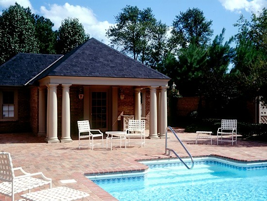Photo of a large traditional backyard rectangular lap pool in Toronto with a pool house and brick pavers.