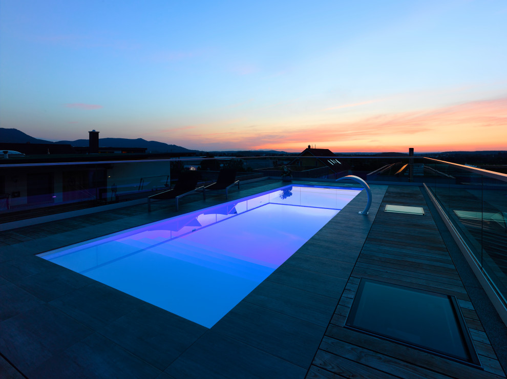 Design ideas for a mid-sized modern rooftop rectangular pool in Stuttgart with natural stone pavers.