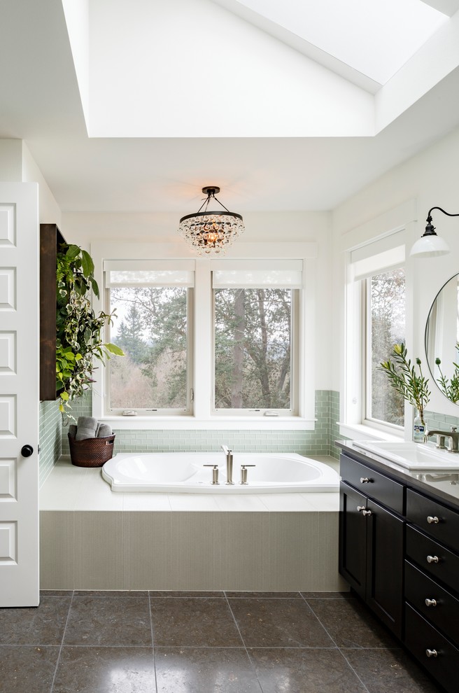 Design ideas for a large transitional master bathroom in Portland with a drop-in sink, a drop-in tub, green tile, white walls, shaker cabinets, black cabinets, glass tile, porcelain floors and granite benchtops.