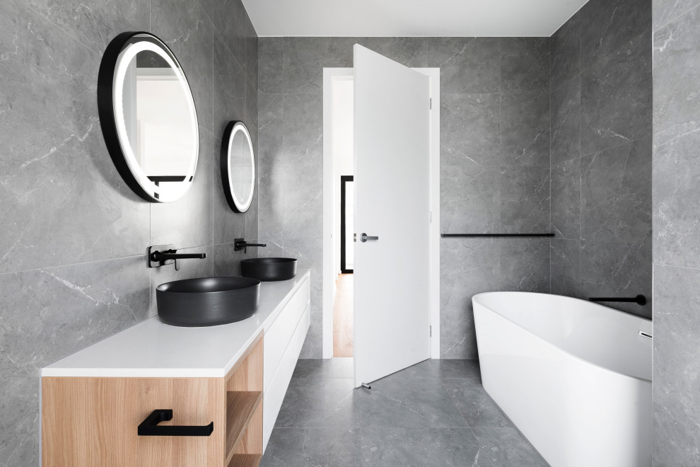 Design ideas for a mid-sized modern master bathroom in San Francisco with flat-panel cabinets, white cabinets, a freestanding tub, a shower/bathtub combo, a wall-mount toilet, gray tile, stone tile, grey walls, ceramic floors, a vessel sink, granite benchtops, grey floor, white benchtops, a shower seat, a double vanity, a floating vanity, wood and wood walls.