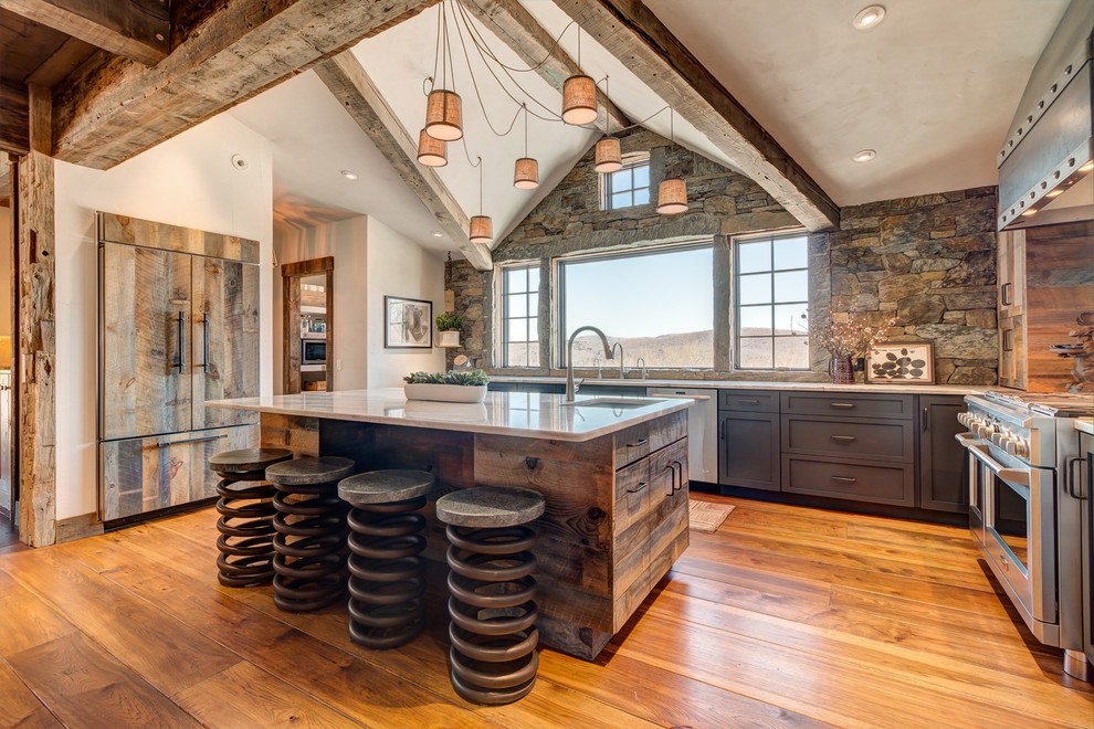 Inspiration for a rustic l-shaped medium tone wood floor kitchen remodel in Burlington with an undermount sink, shaker cabinets, gray cabinets, paneled appliances and an island