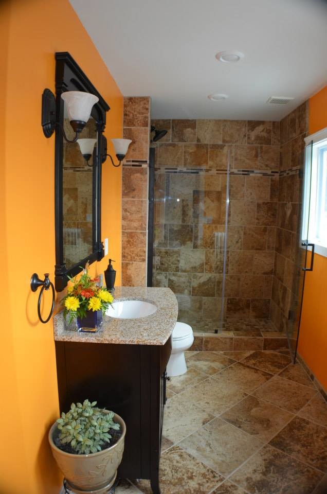 This is an example of a mid-sized contemporary master bathroom in New York with furniture-like cabinets, dark wood cabinets, an open shower, a two-piece toilet, beige tile, porcelain tile, orange walls, porcelain floors and laminate benchtops.