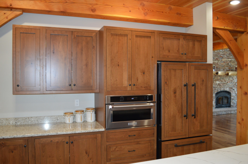 Example of a mid-sized mountain style u-shaped medium tone wood floor, brown floor and exposed beam eat-in kitchen design with a farmhouse sink, shaker cabinets, medium tone wood cabinets, paneled appliances and an island
