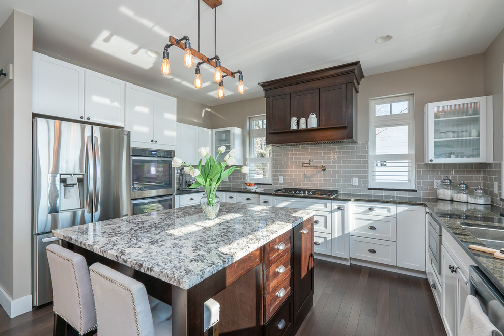 Inspiration for a large transitional u-shaped kitchen in Detroit with white cabinets, grey splashback, stainless steel appliances, dark hardwood floors, with island, brown floor, a double-bowl sink, flat-panel cabinets, granite benchtops, ceramic splashback and multi-coloured benchtop.