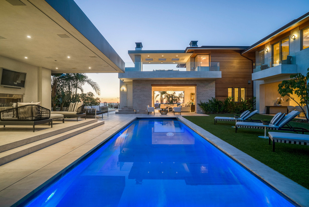 Large beach style backyard rectangular lap pool in Los Angeles with a pool house and concrete pavers.