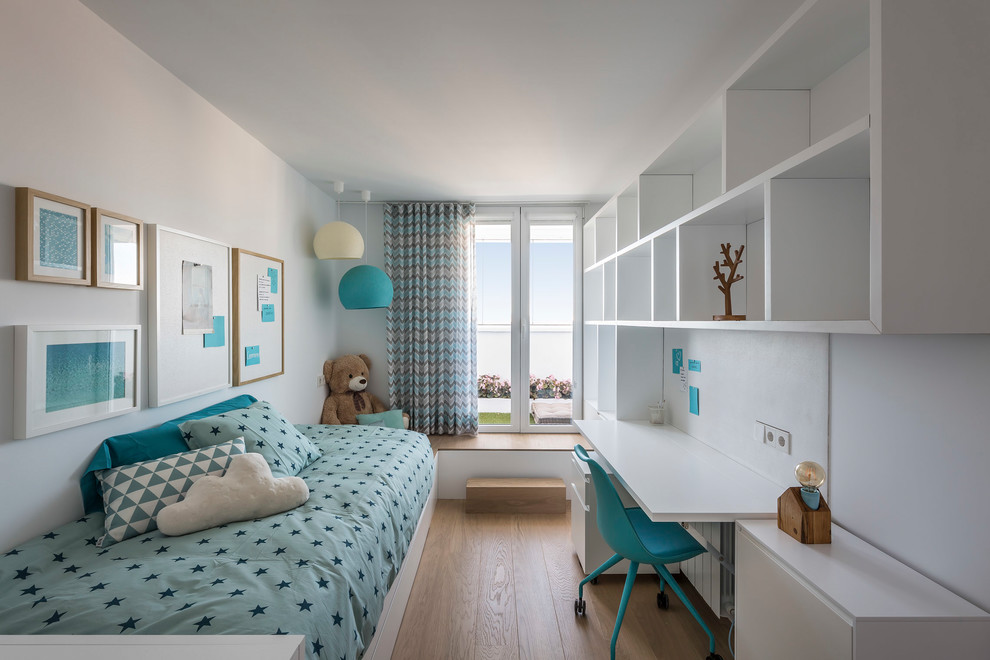 This is an example of a contemporary kids' room for girls in Valencia with white walls and light hardwood floors.
