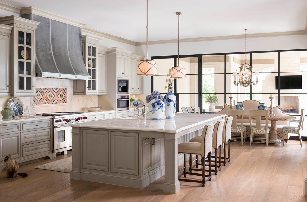 This is an example of a traditional kitchen in Dallas with beaded inset cabinets, grey cabinets, multi-coloured splashback, stainless steel appliances, light hardwood floors and with island.